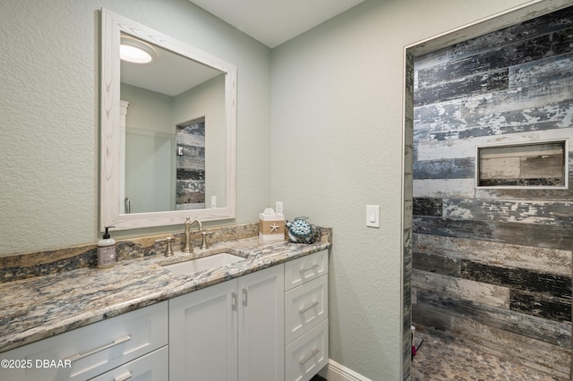 full bathroom with a textured wall and vanity