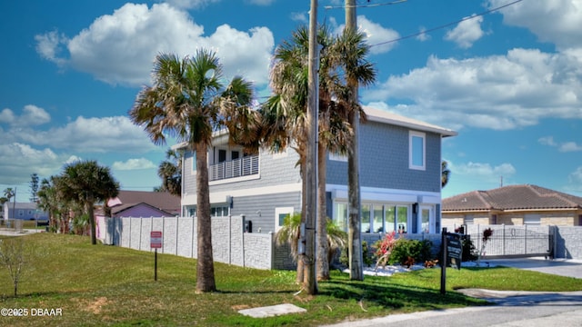 exterior space with a balcony, a front yard, and fence