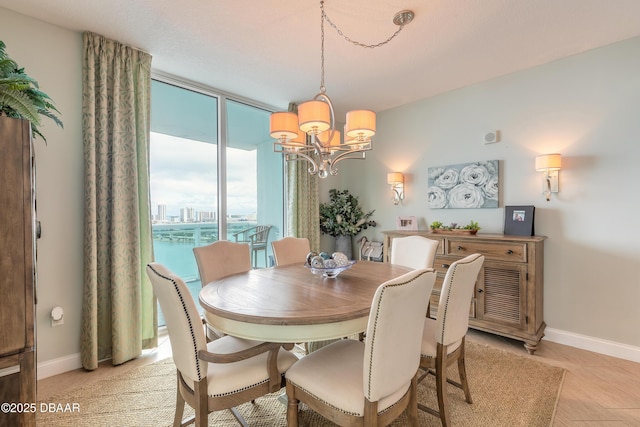 dining room featuring a chandelier, expansive windows, a city view, and baseboards