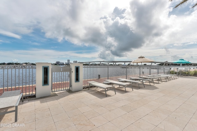 view of patio with a water view, fence, and a gate