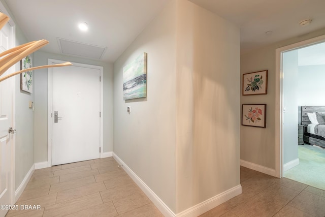 hall featuring attic access and baseboards