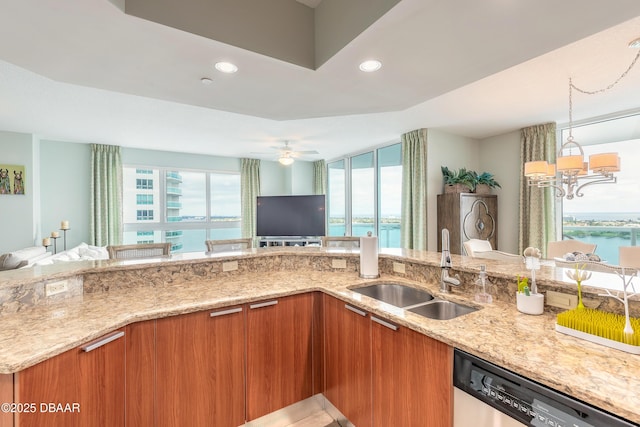 kitchen featuring open floor plan, a sink, dishwasher, and light stone countertops