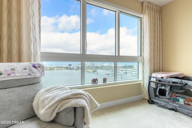 carpeted bedroom featuring a water view and baseboards