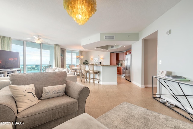 living room featuring baseboards, visible vents, a wall of windows, a textured ceiling, and ceiling fan with notable chandelier