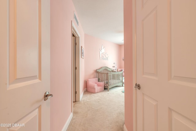 corridor featuring light carpet, visible vents, and baseboards