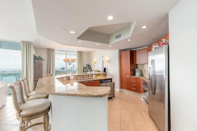 kitchen featuring decorative light fixtures, a raised ceiling, visible vents, appliances with stainless steel finishes, and a sink