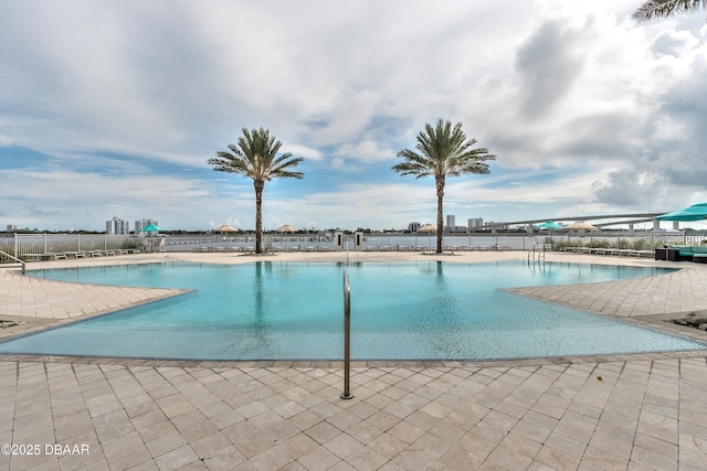 community pool with a patio area and fence