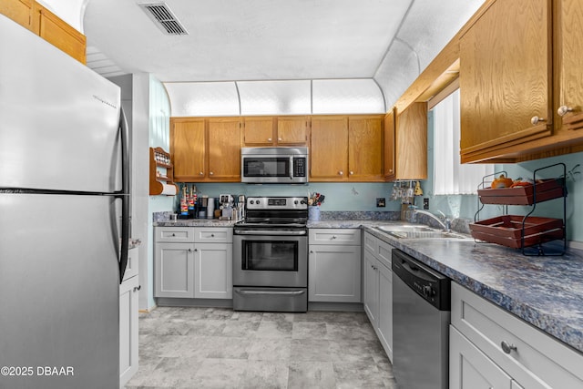 kitchen featuring stainless steel appliances, a sink, and dark countertops