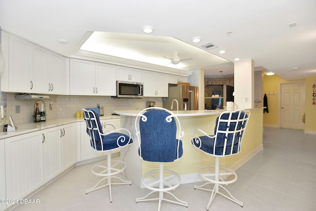 kitchen with white cabinets, light tile patterned flooring, backsplash, and appliances with stainless steel finishes