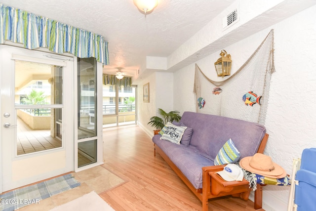 interior space with a wealth of natural light, a textured ceiling, hardwood / wood-style flooring, and ceiling fan