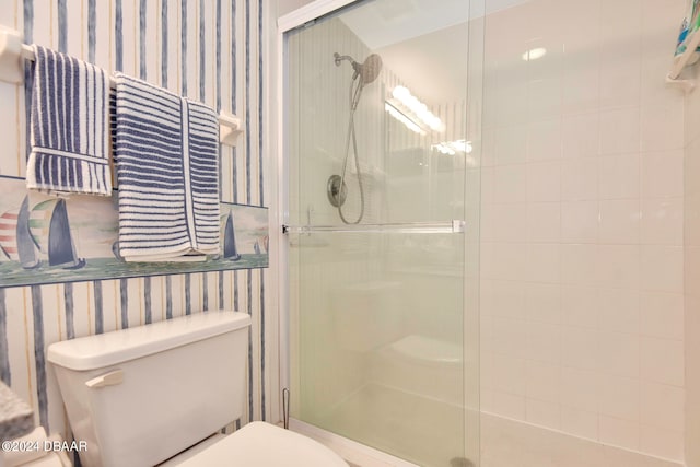 bathroom featuring toilet and a shower with shower door