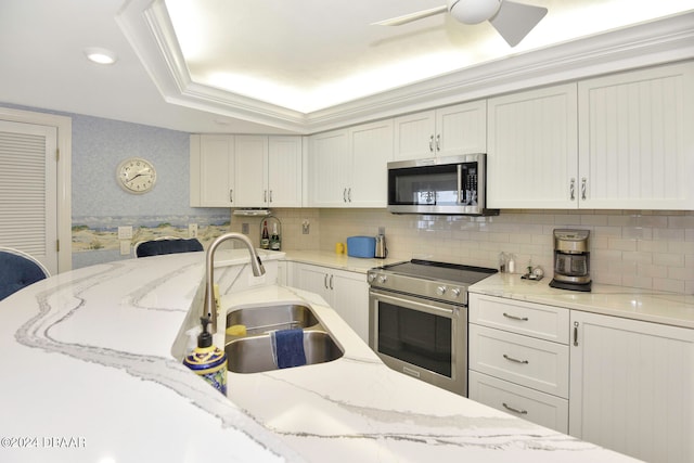 kitchen featuring stainless steel appliances, ceiling fan, sink, and light stone counters