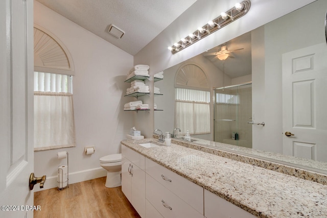 bathroom with visible vents, toilet, a shower with door, ceiling fan, and wood finished floors