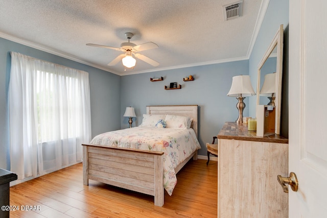 bedroom with a textured ceiling, ornamental molding, wood finished floors, and visible vents