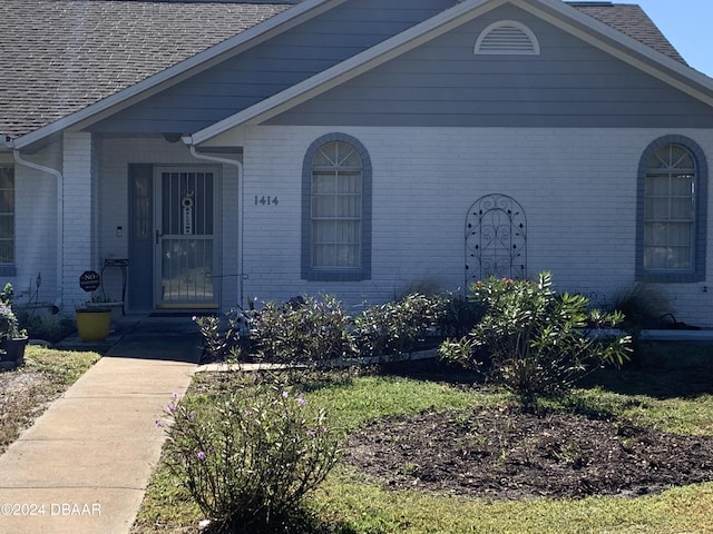 property entrance with brick siding and roof with shingles