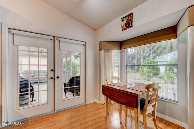 dining area featuring light wood-type flooring, french doors, vaulted ceiling, and baseboards