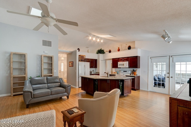 living area with a textured ceiling, light wood-style flooring, visible vents, vaulted ceiling, and french doors