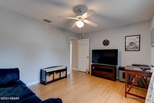 living room with light wood finished floors, baseboards, visible vents, and ceiling fan