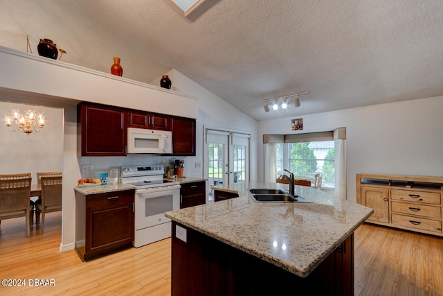 kitchen with white appliances, a sink, vaulted ceiling, reddish brown cabinets, and light wood finished floors