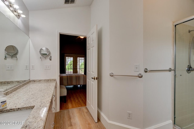 full bath with french doors, visible vents, a tile shower, vanity, and wood finished floors