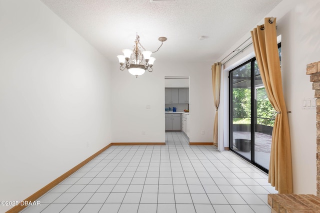 interior space with a chandelier, a textured ceiling, baseboards, and light tile patterned flooring