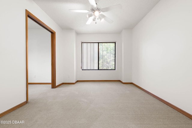 spare room featuring light carpet, baseboards, and a textured ceiling