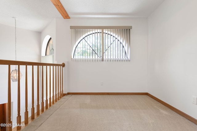 empty room with baseboards, beamed ceiling, and carpet floors