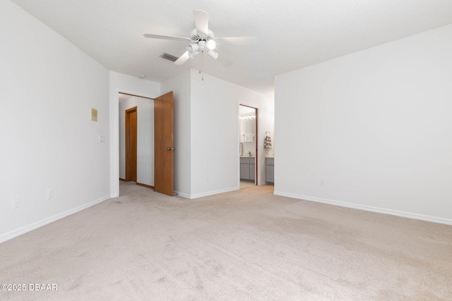 interior space with ceiling fan, a textured ceiling, light colored carpet, visible vents, and baseboards