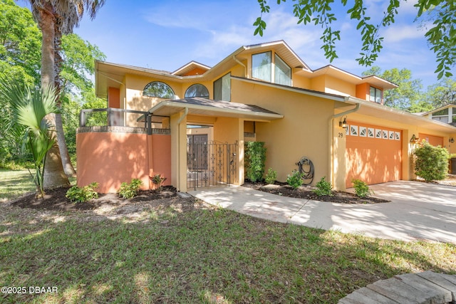 view of front facade with an attached garage, a gate, driveway, and stucco siding