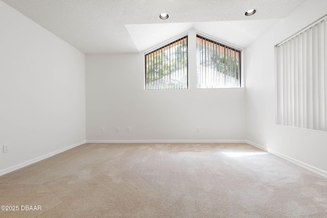 spare room with lofted ceiling, a textured ceiling, baseboards, and carpet floors