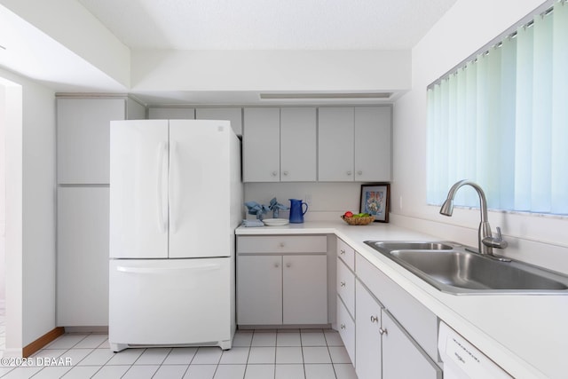kitchen featuring a sink, light countertops, white appliances, and light tile patterned flooring