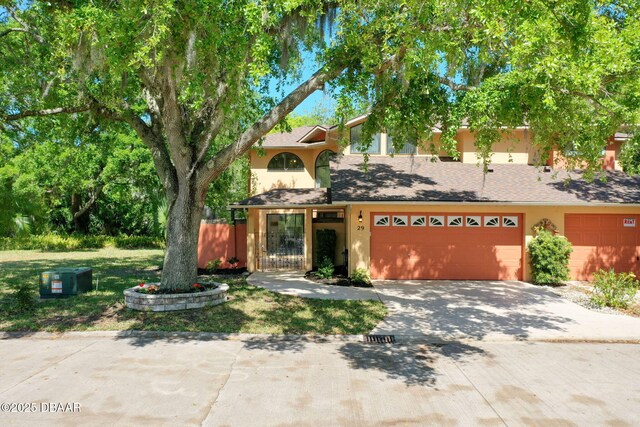 view of front facade with a shingled roof, driveway, and stucco siding