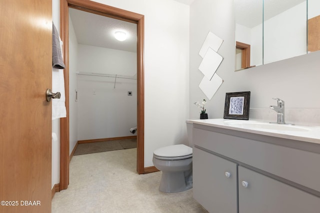 bathroom featuring toilet, a spacious closet, a textured ceiling, vanity, and tile patterned floors