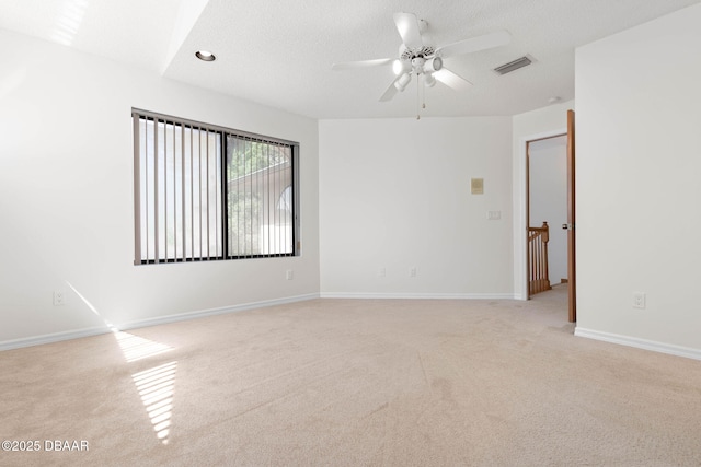 unfurnished room featuring baseboards, light carpet, a textured ceiling, a ceiling fan, and visible vents