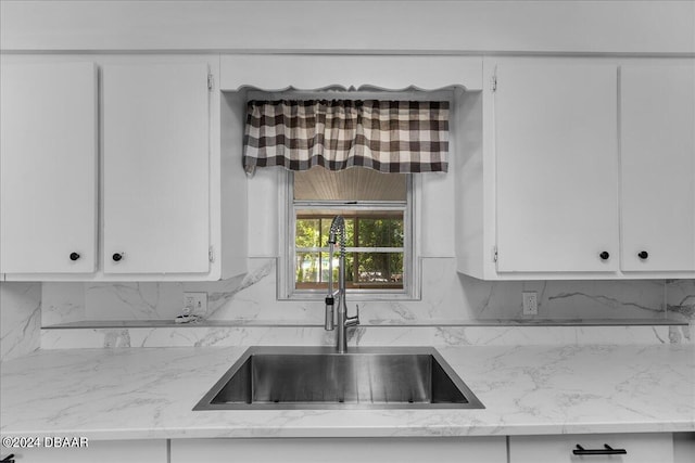 kitchen featuring white cabinetry, sink, and light stone counters