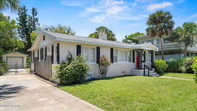 view of front of house with a front yard, a garage, and an outdoor structure