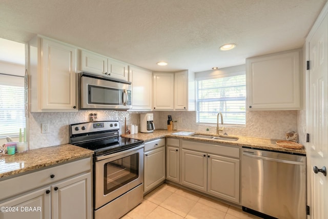 kitchen featuring white cabinetry, sink, stainless steel appliances, a textured ceiling, and light tile patterned floors