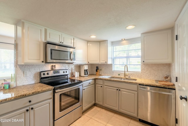 415 Banana Cay Dr Unit F, South Daytona, FL 32119 - kitchen featuring stainless steel appliances, a sink, decorative backsplash, white cabinetry, and light tile patterned floors