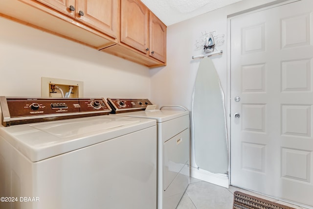 laundry area with light tile patterned flooring, cabinets, separate washer and dryer, and a textured ceiling