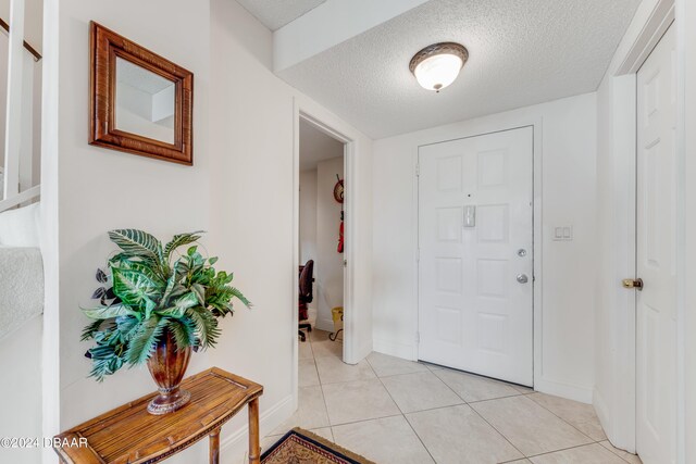901 S Atlantic Ave Unit 102, Ormond Beach, FL 32176 - entryway featuring a textured ceiling, light tile patterned floors, stairs, and baseboards