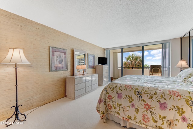 bedroom featuring light carpet, a textured ceiling, access to outside, and expansive windows