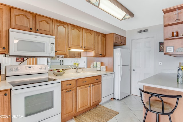 kitchen with light tile patterned flooring, white appliances, and sink