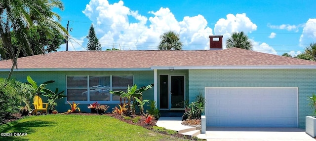 ranch-style home with a garage, concrete driveway, roof with shingles, a front lawn, and brick siding