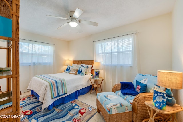 tiled bedroom featuring ceiling fan, multiple windows, and a textured ceiling