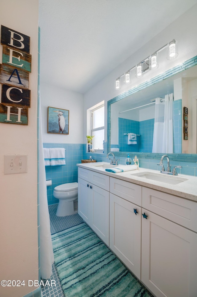 bathroom featuring toilet, double vanity, tile walls, and a sink