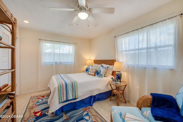 bedroom featuring ceiling fan, multiple windows, baseboards, and tile patterned floors