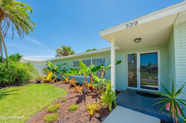 doorway to property with a yard and brick siding