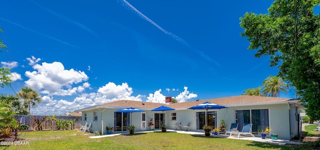 rear view of property featuring a yard, a chimney, fence, and a patio