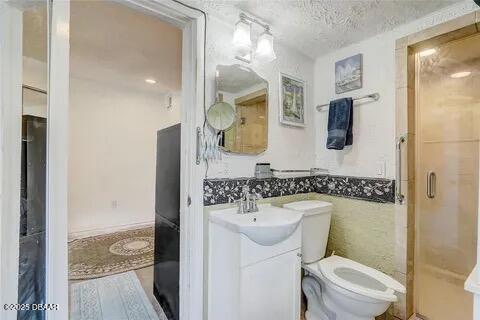 2144 Ridge Dr, Winter Park, FL 32792 - bathroom featuring toilet, vanity, a wainscoted wall, a shower stall, and a textured ceiling