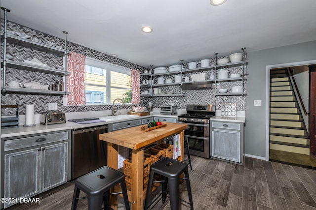 kitchen featuring sink, appliances with stainless steel finishes, tasteful backsplash, dark hardwood / wood-style floors, and range hood